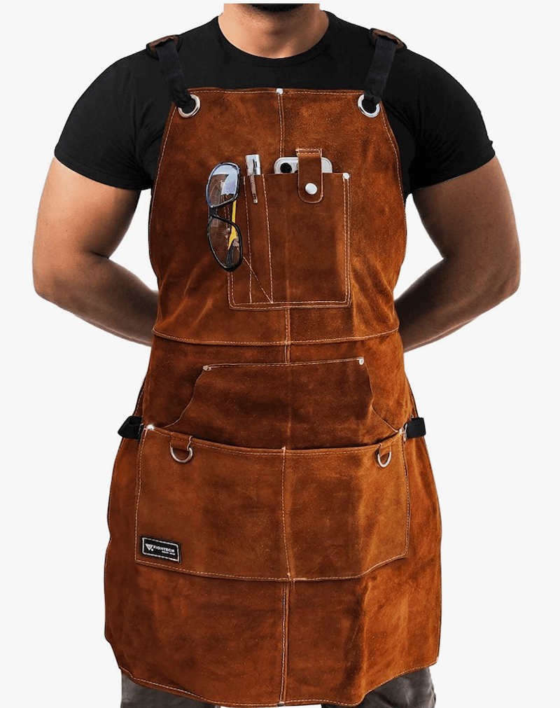 A man wearing a black T-shirt under a brown leather tool apron