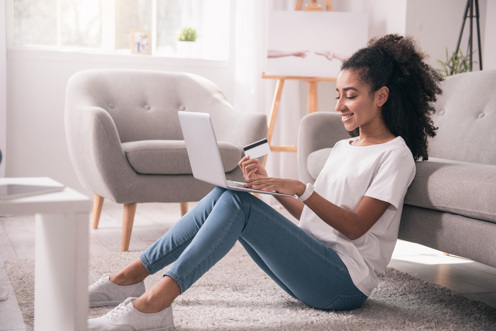 Credit card payment due date vs closing date: A woman smiles while using her credit card and her laptop