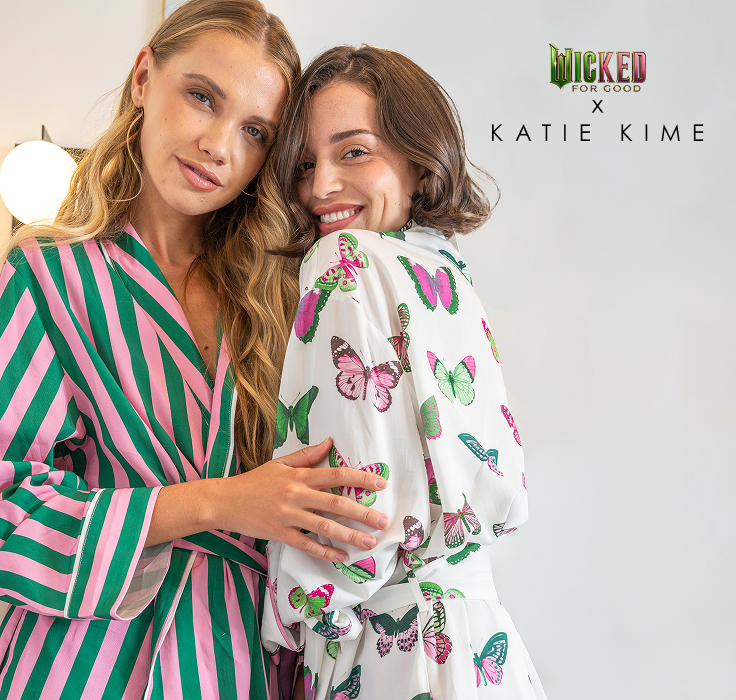 two women wearing Wicked: For Good x Katie Kime Lounge Robes in the retro stripe and mariposa print