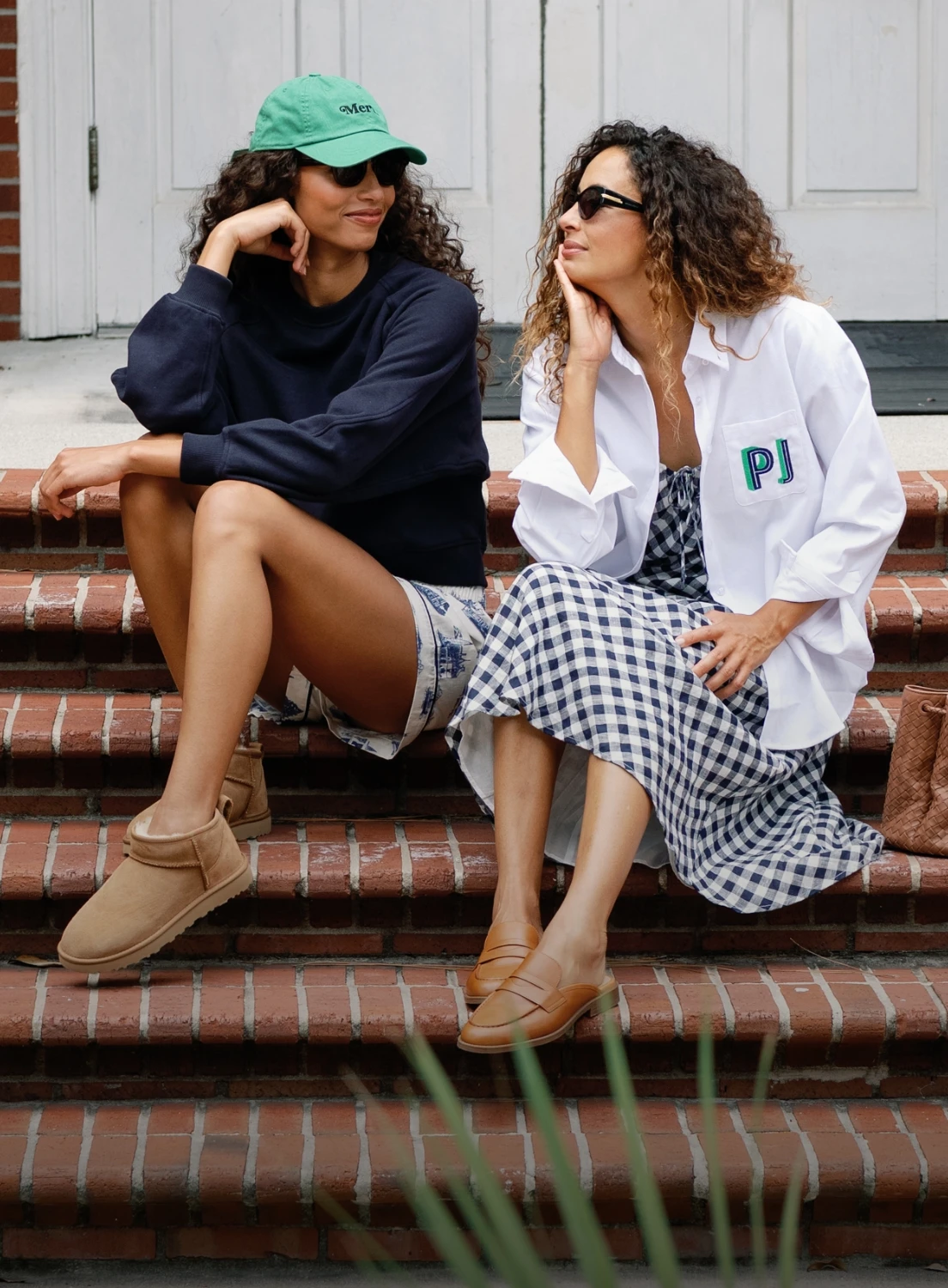two women sitting on the steps. One woman is wearing a classic charlotte button down white oxford with embroidered initials on the pocket