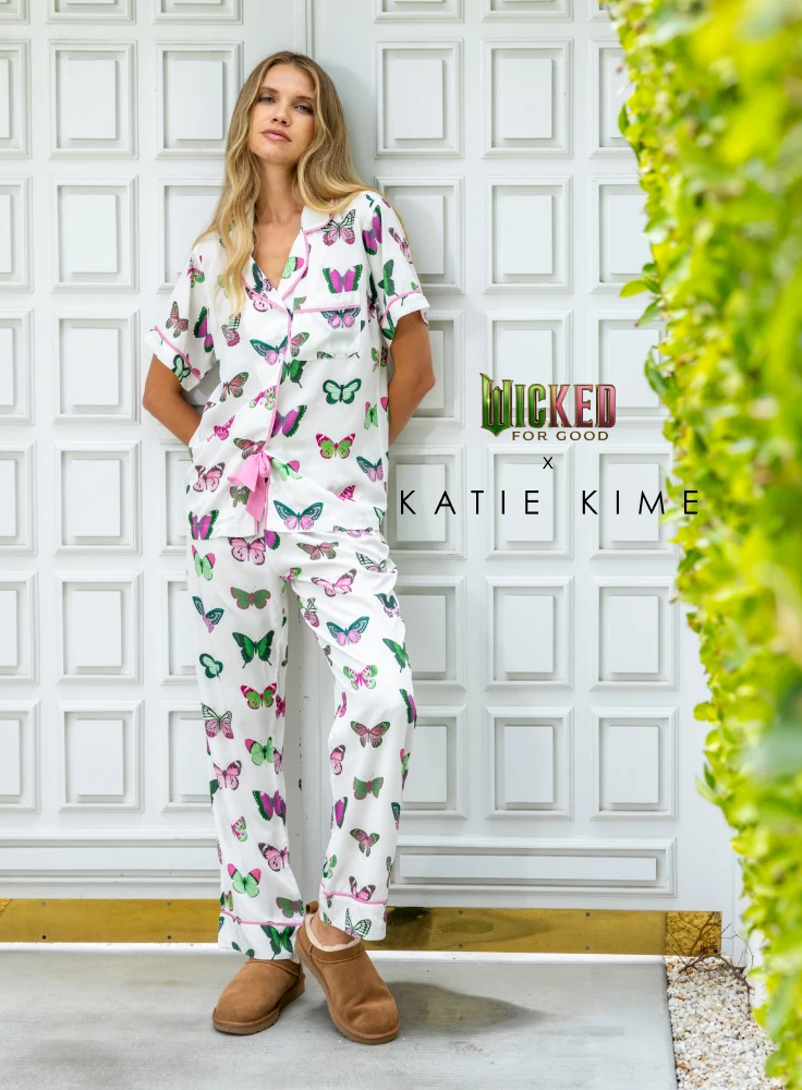 a woman leaning on a door wearing the new katie kime Wicked collaboration "Mariposa" print pajama set in pants