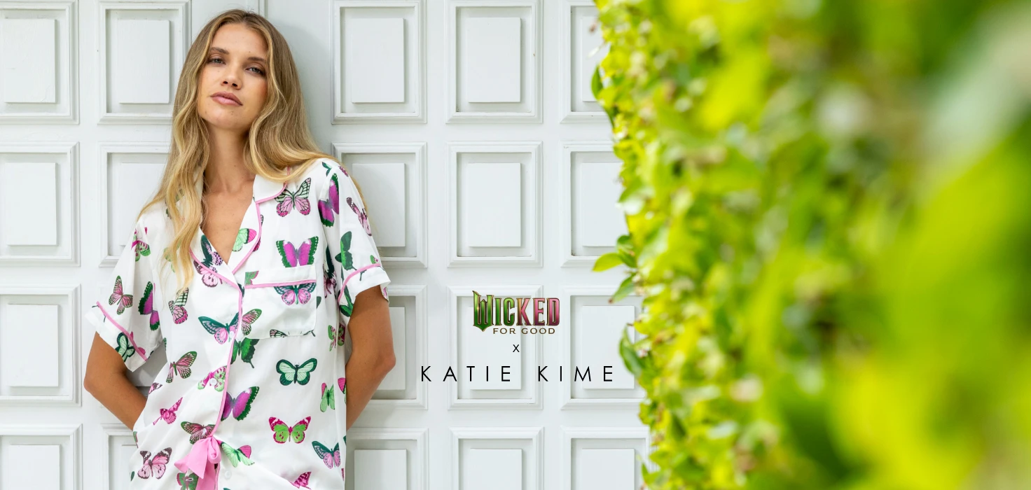 a woman leaning on a door wearing the new katie kime Wicked collaboration "Mariposa" print pajama set in pants