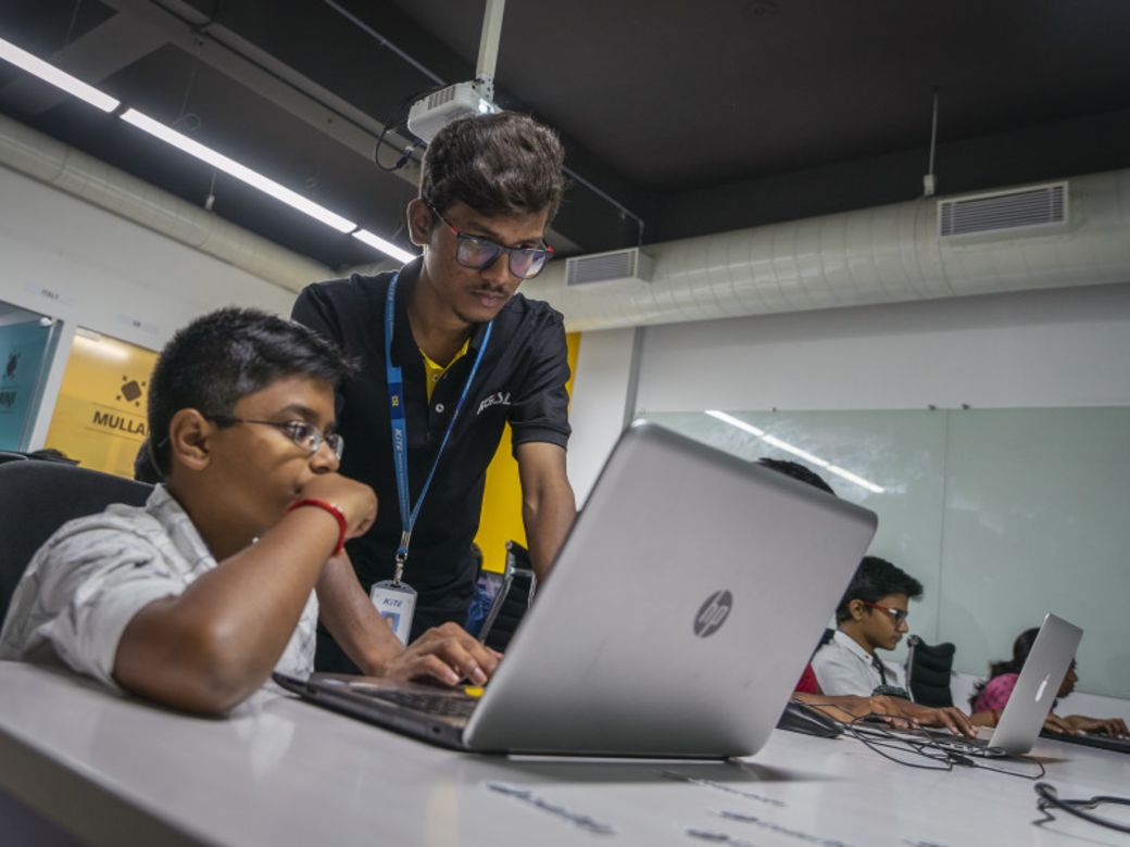 Man mentoring a boy with a laptop