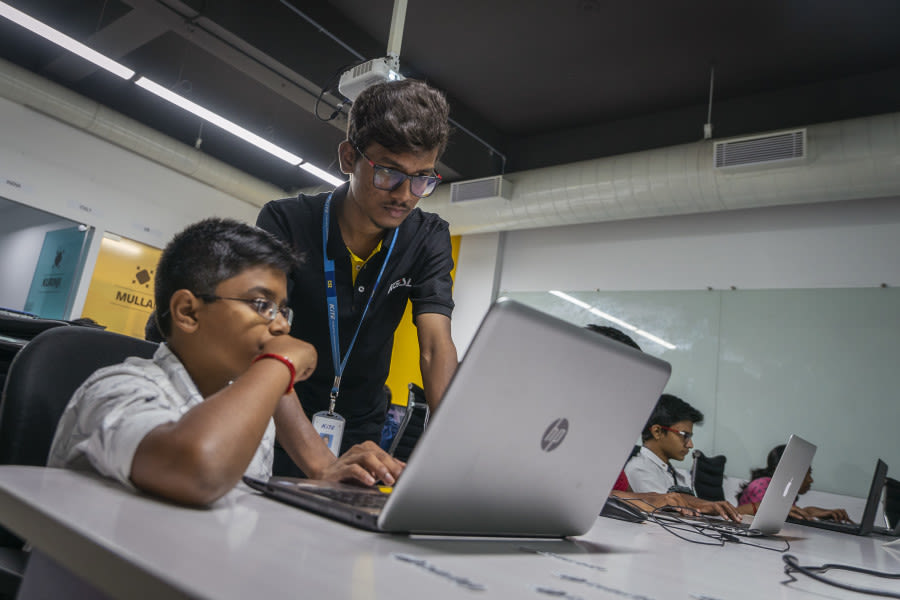 Man mentoring a boy with a laptop