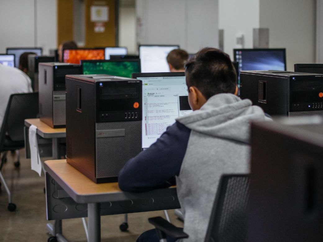 Boy seated at a computer with his back to the camera