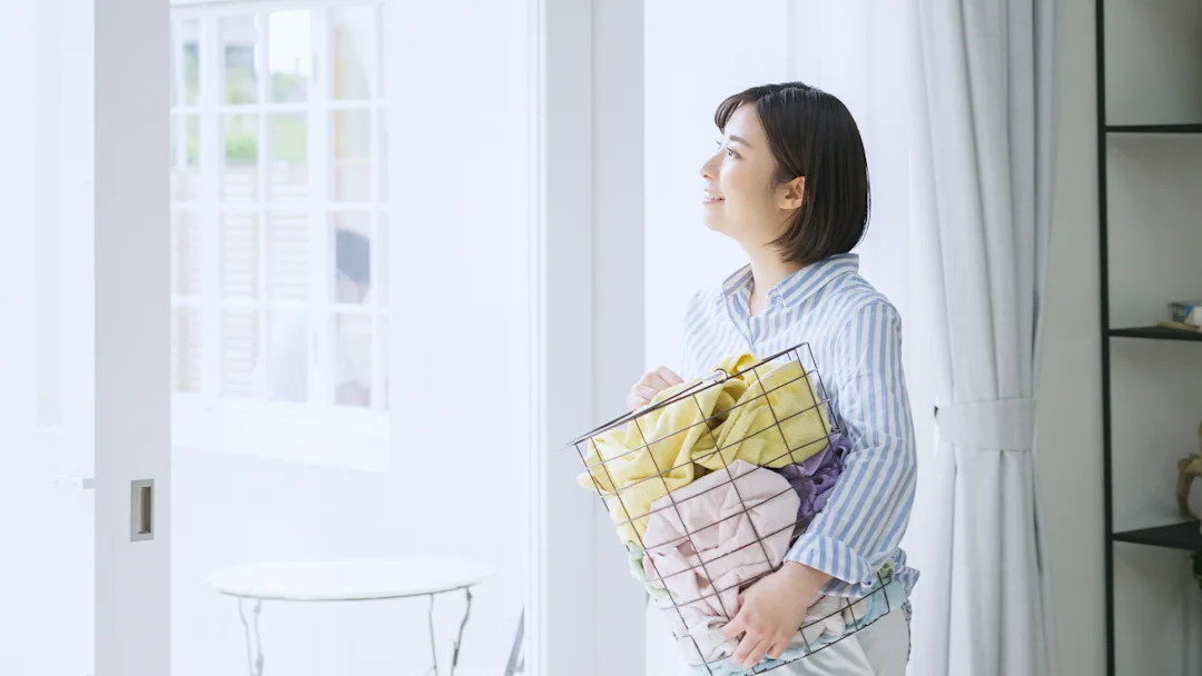 Woman Holding Laundry Basket In Front Of A Window