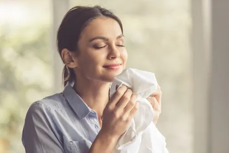 Woman Savoring The Fresh Scent Of Clothes Indoors