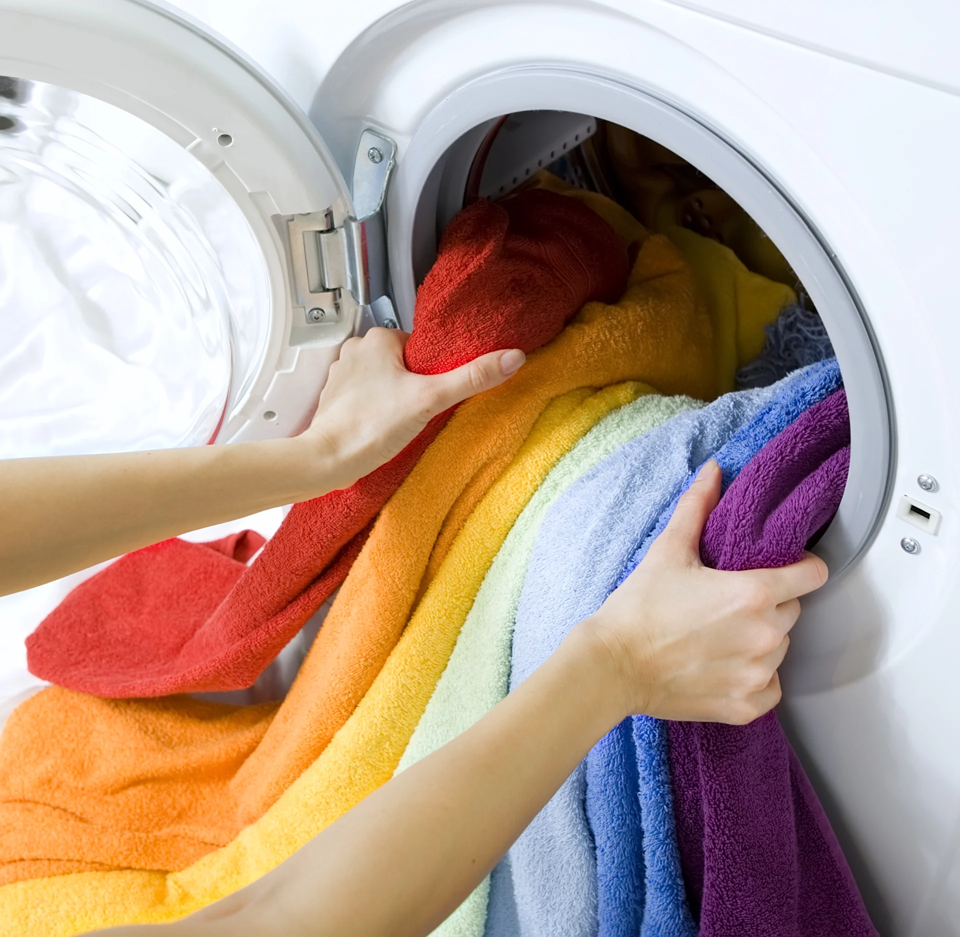 Colorful Clothes Being Loaded Into A Front-Load Washing Machine
