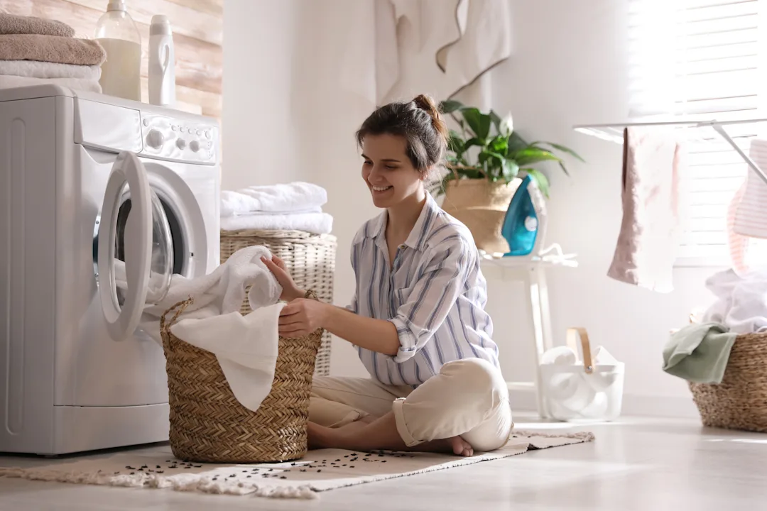 Woman Placing Laundry In Washing Machine In A Bright Room