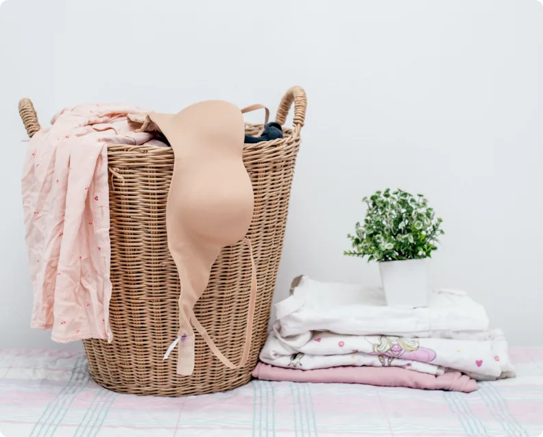 Laundry Basket With Clothes Beside Neatly Folded Fabric