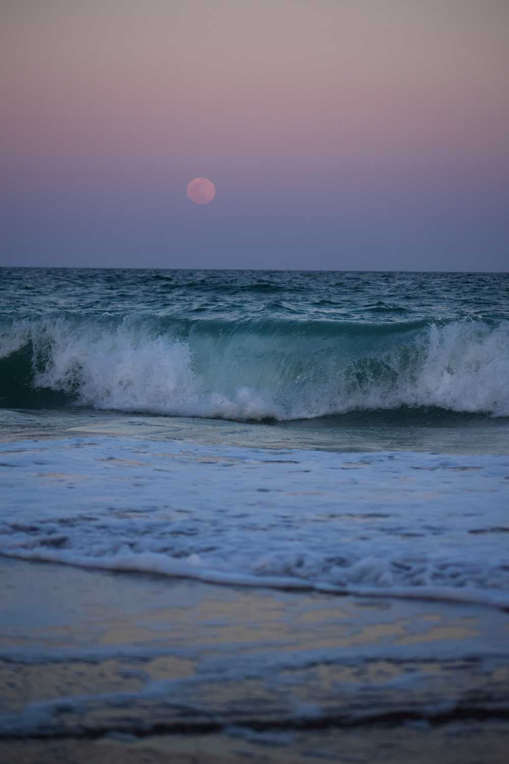 Ocean waves crashing on shore during sunset