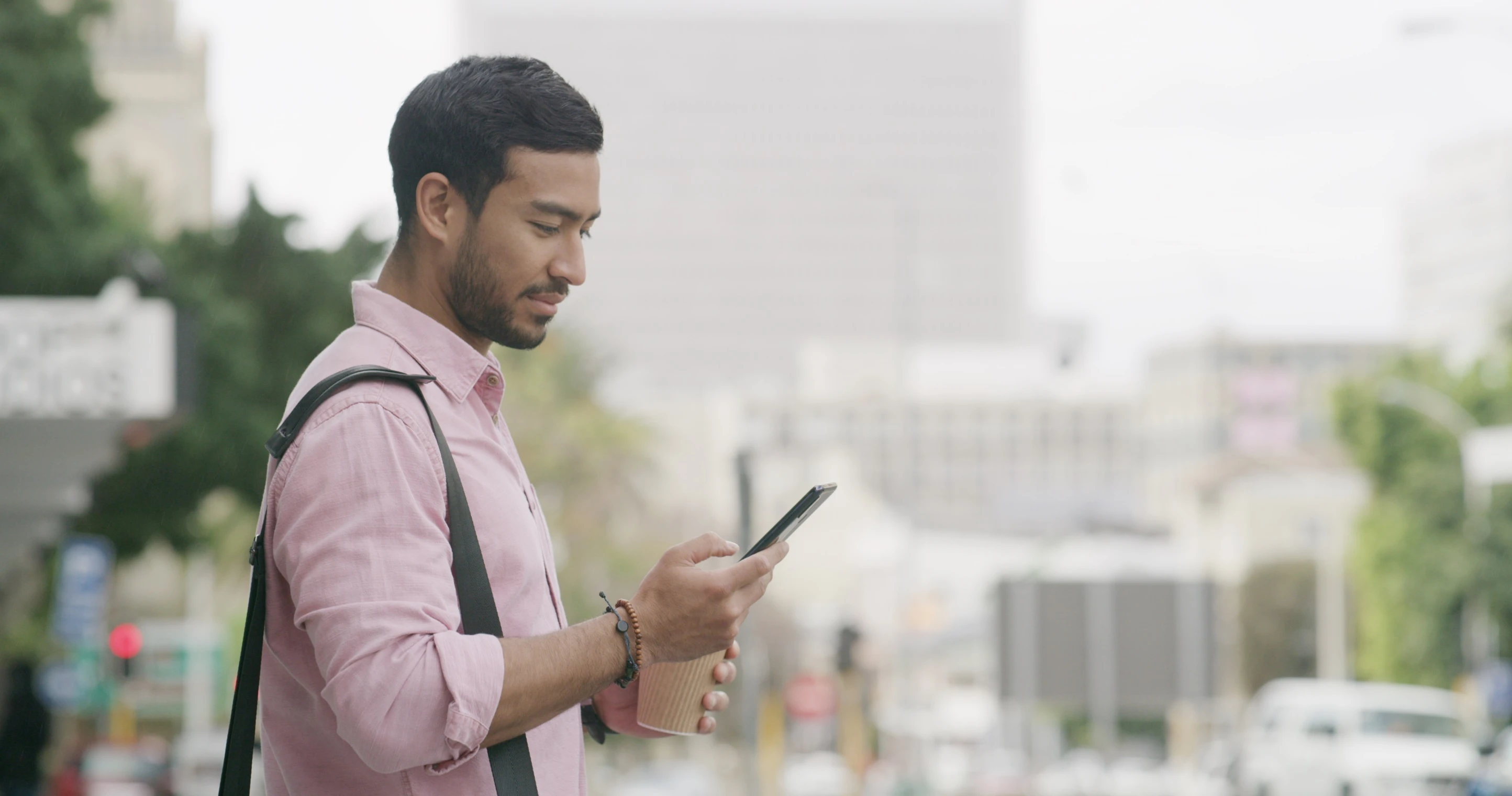 A man looking at his phone while walking down the street.