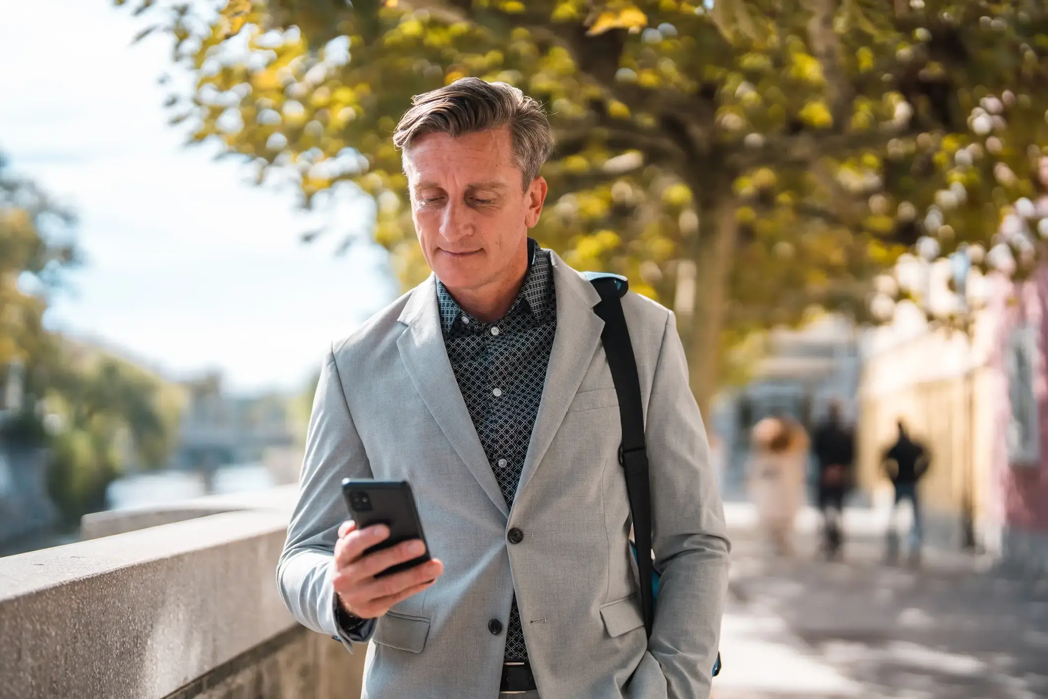 Business owner walking outside while looking at his phone.