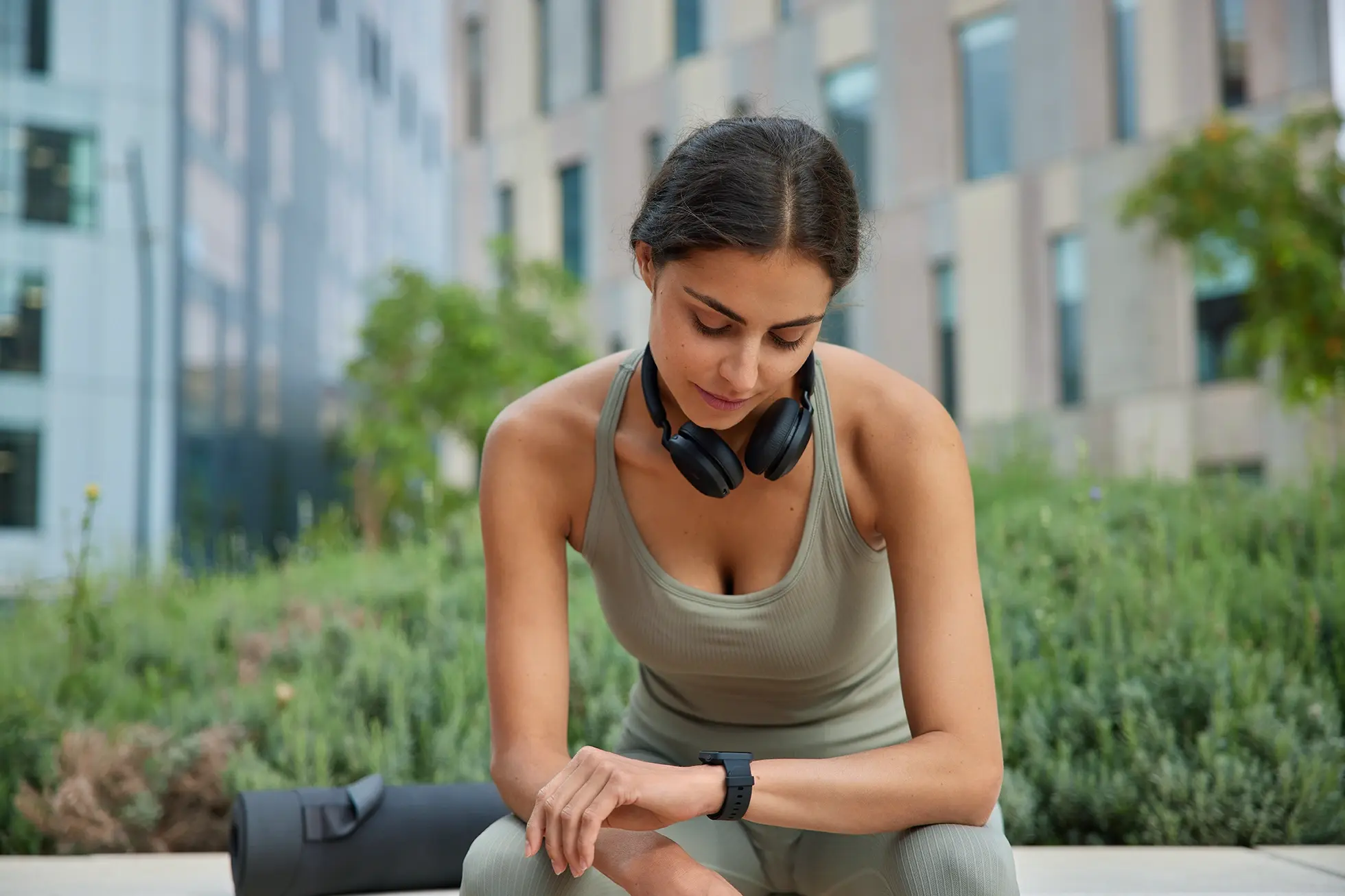 A woman wearing a smart watch sitting on an outdoor bench.