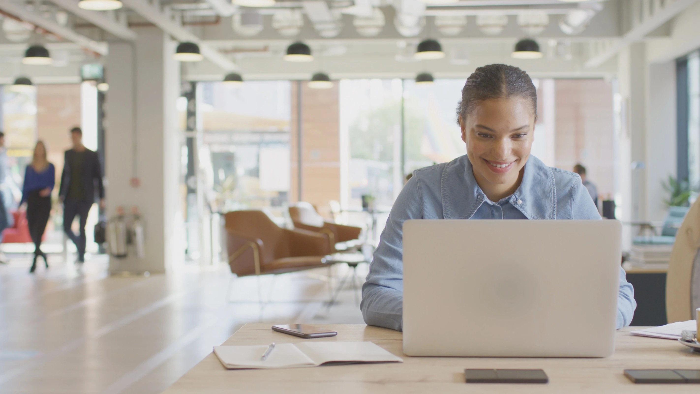 A young, mixed-race woman working on her laptop in an office.