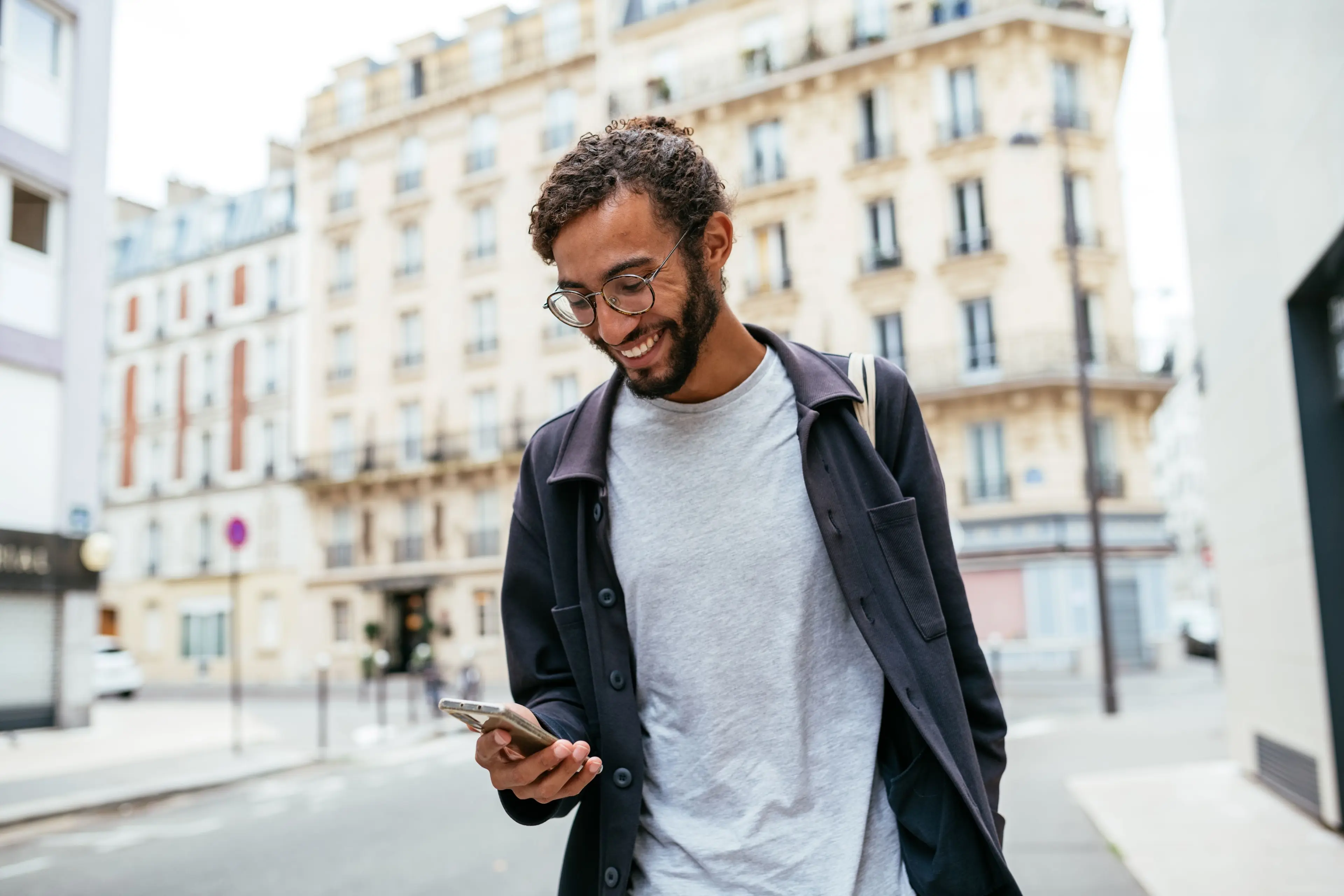 Un homme qui marche dans la rue en regardant son téléphone. 