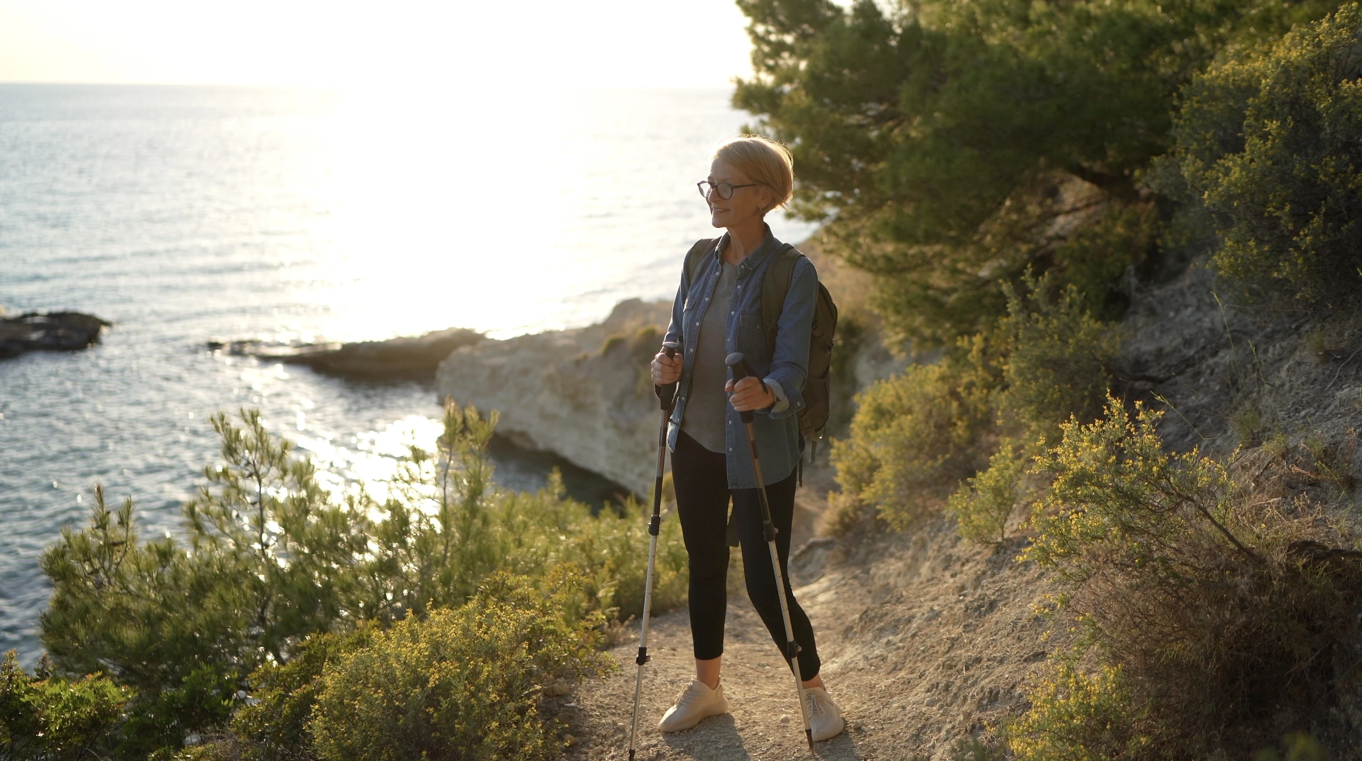 A woman hiking on a trail near the ocean.