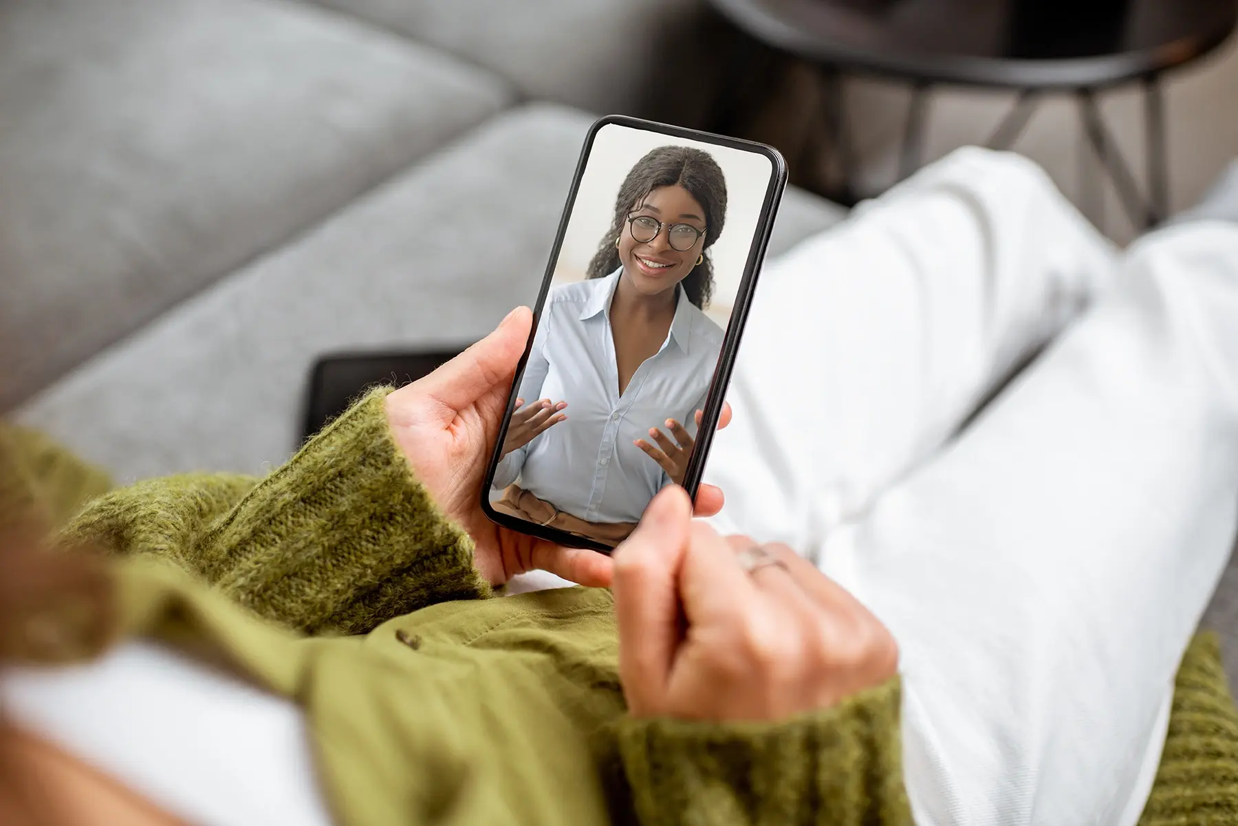 A woman is using a smartphone to take a video call with a medical professional.