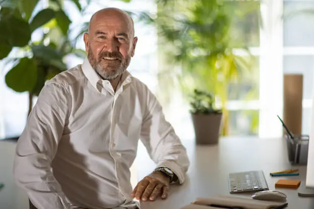 A mature male counselor sitting at a desk in his office.