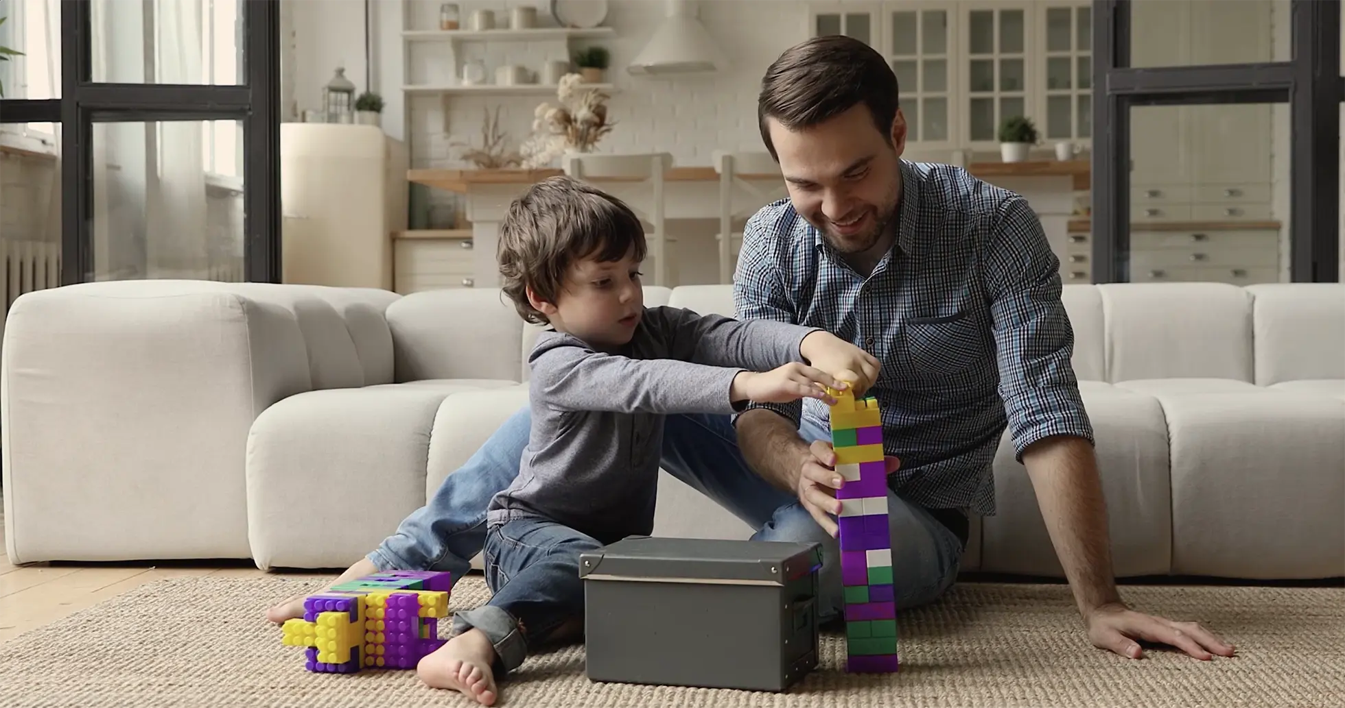 A young father and his son playing with plastic buildings blocks in their living room