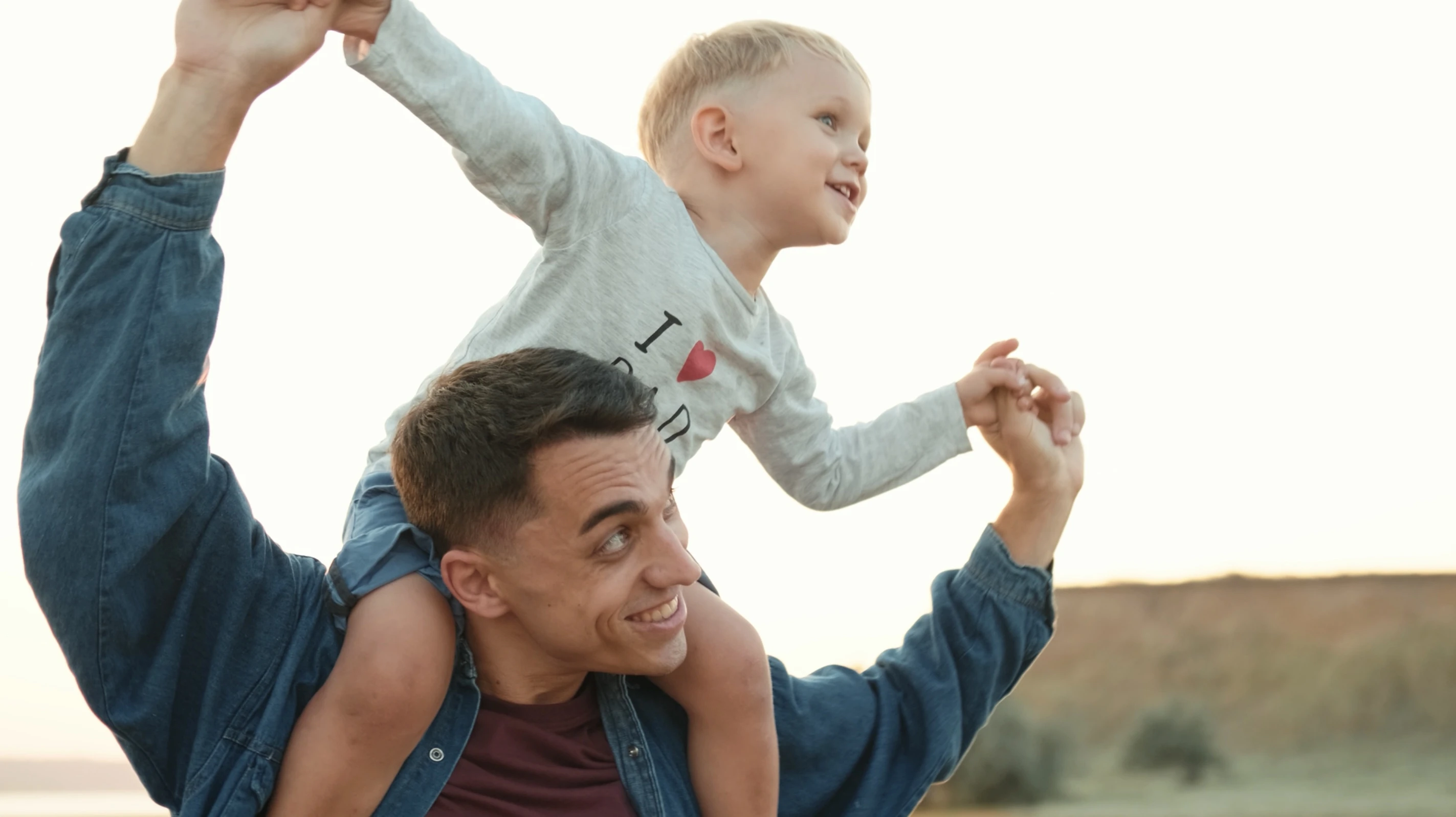 A young man playing with his son while carrying him on his shoulders.