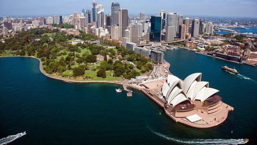 Air view of Sydney with the opera in the foreground, park and buildings.