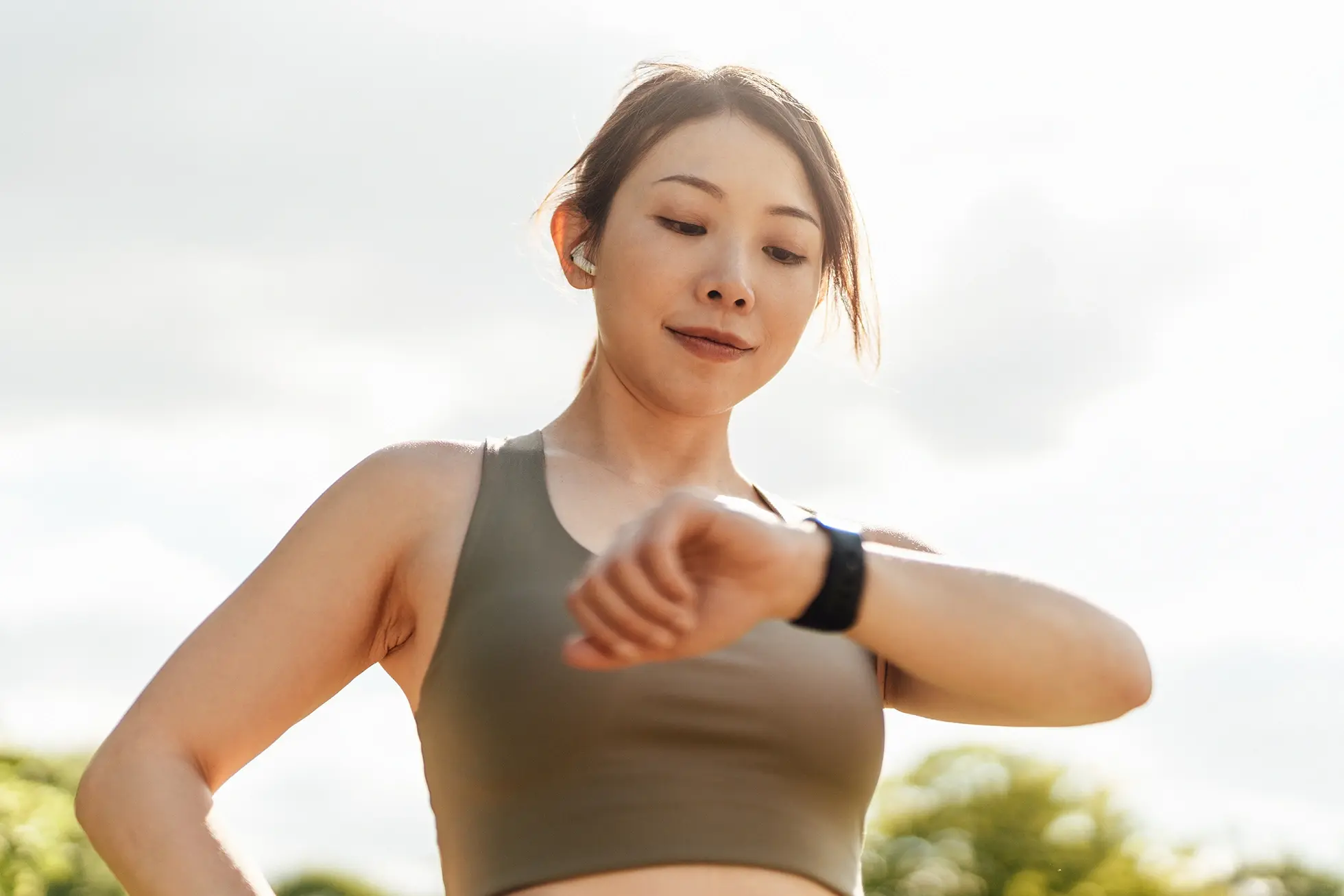Athletic Asian woman checking her smart watch.