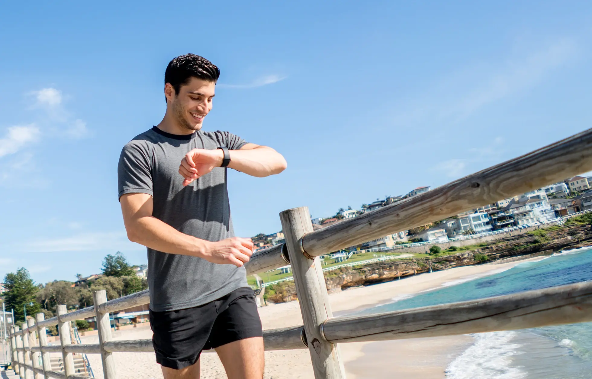 Young man in athletic clothes looking at his smartwatch.