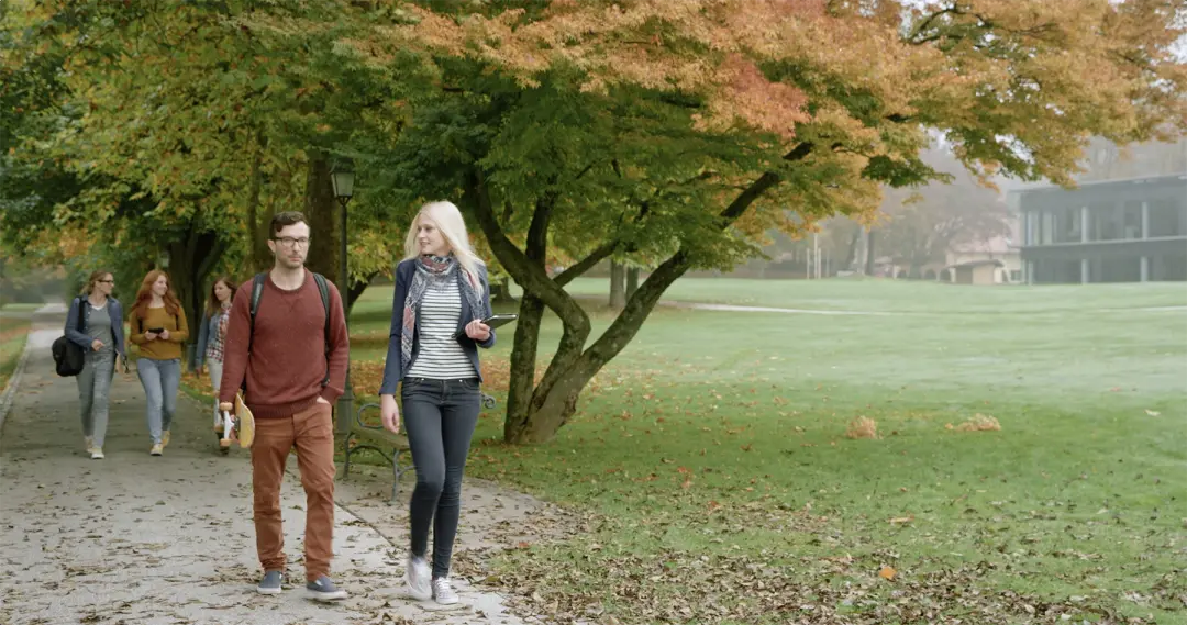 A young man and woman are walking together on campus.