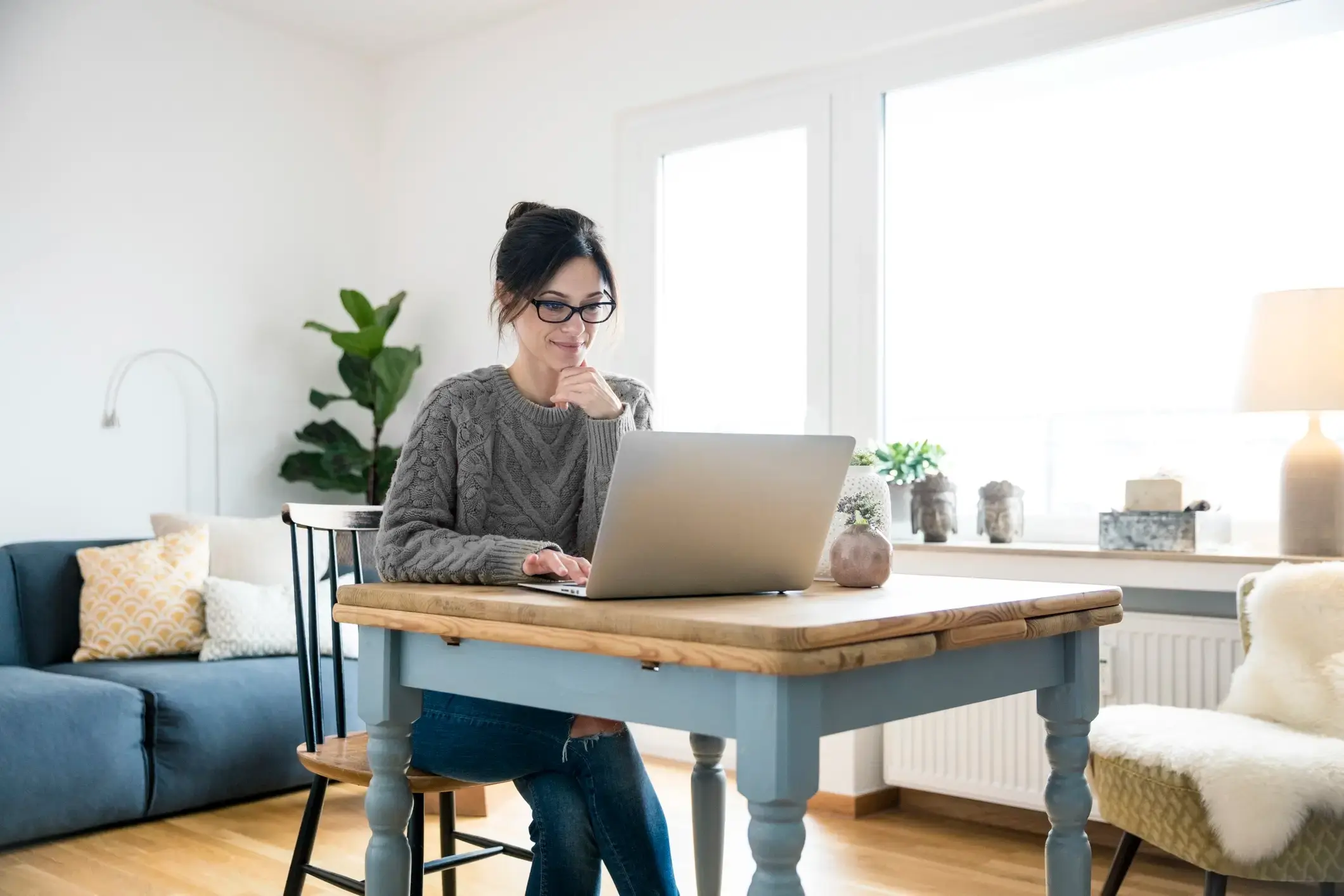 Eine Frau arbeitet an ihrem Computer in ihrem Wohnzimmer.