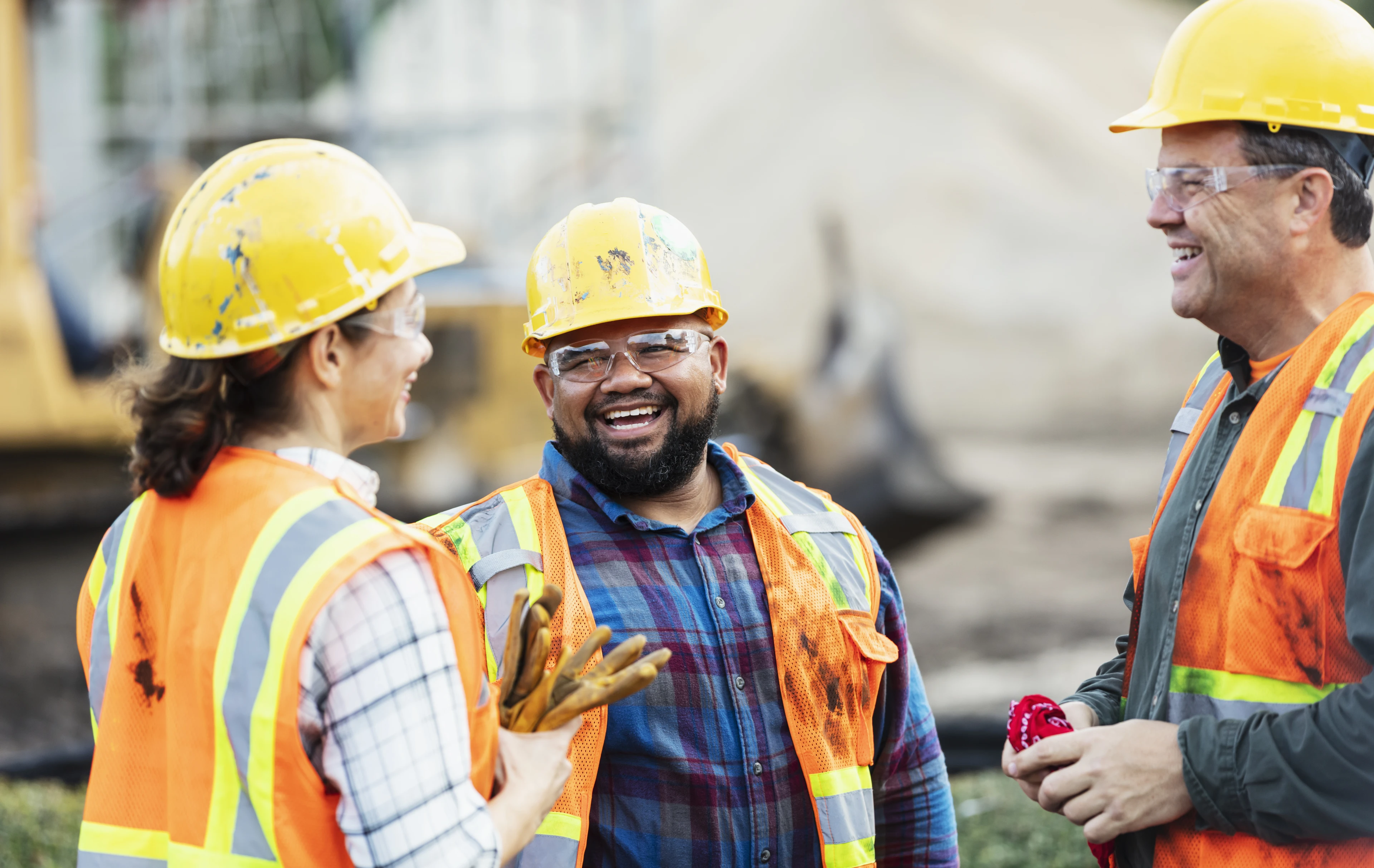 Three construction workers smiling on site.