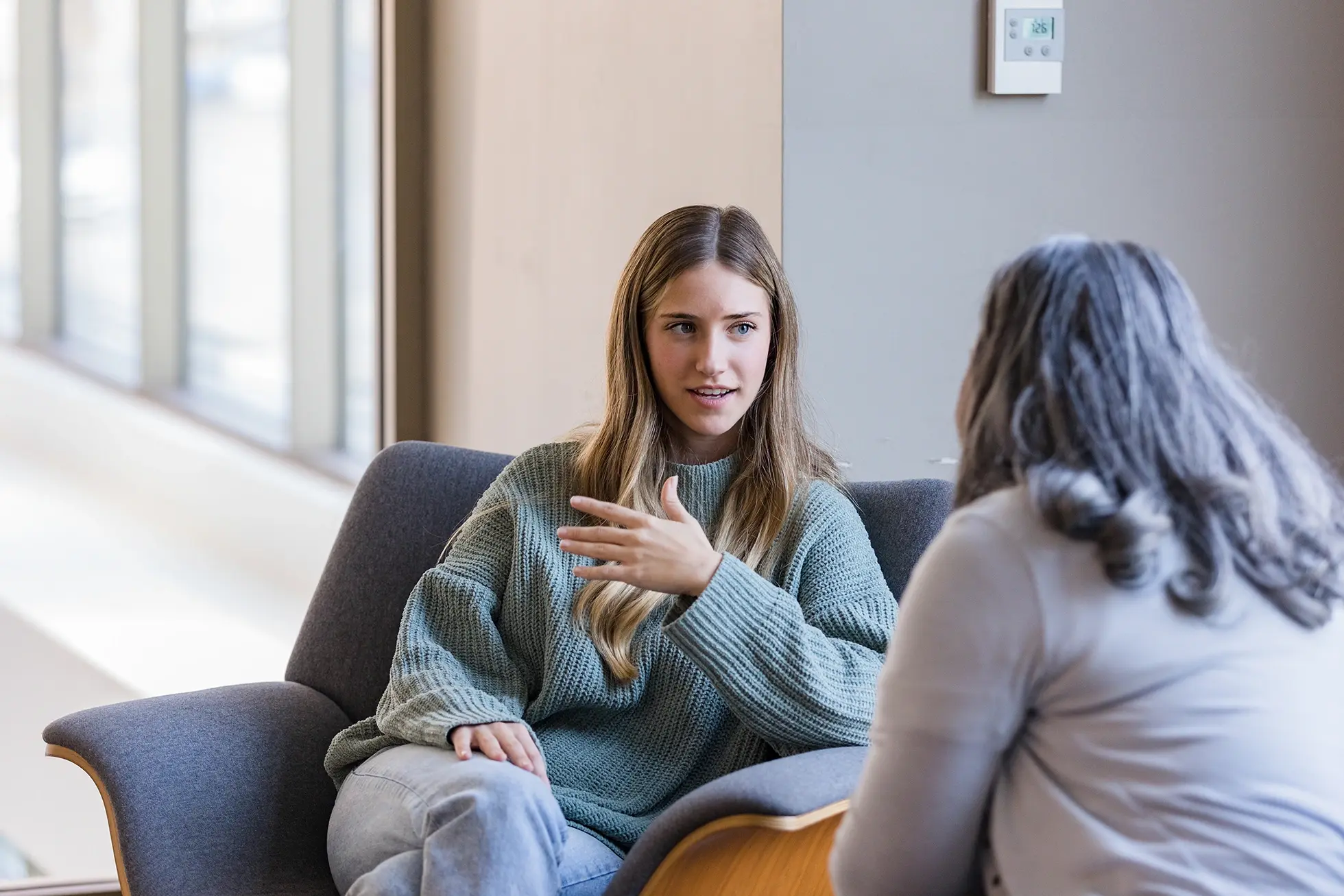 A young woman talking to a female therapist in an office