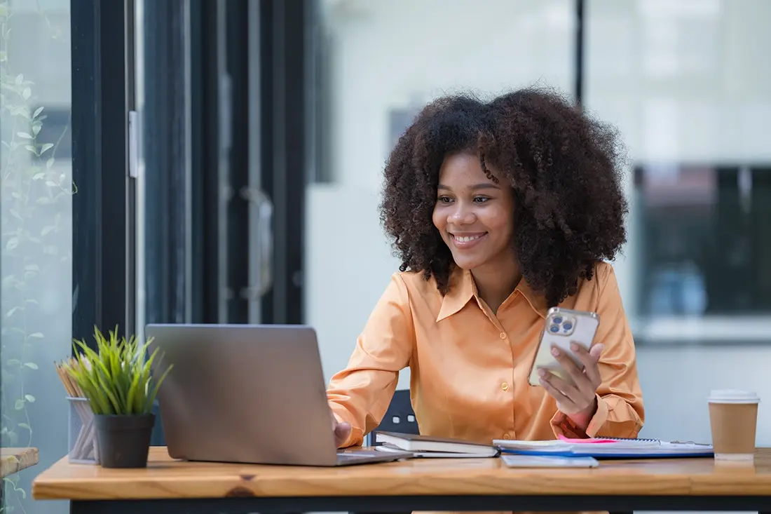 Afro-american woman sitting at a desk with a laptop and a credit card.