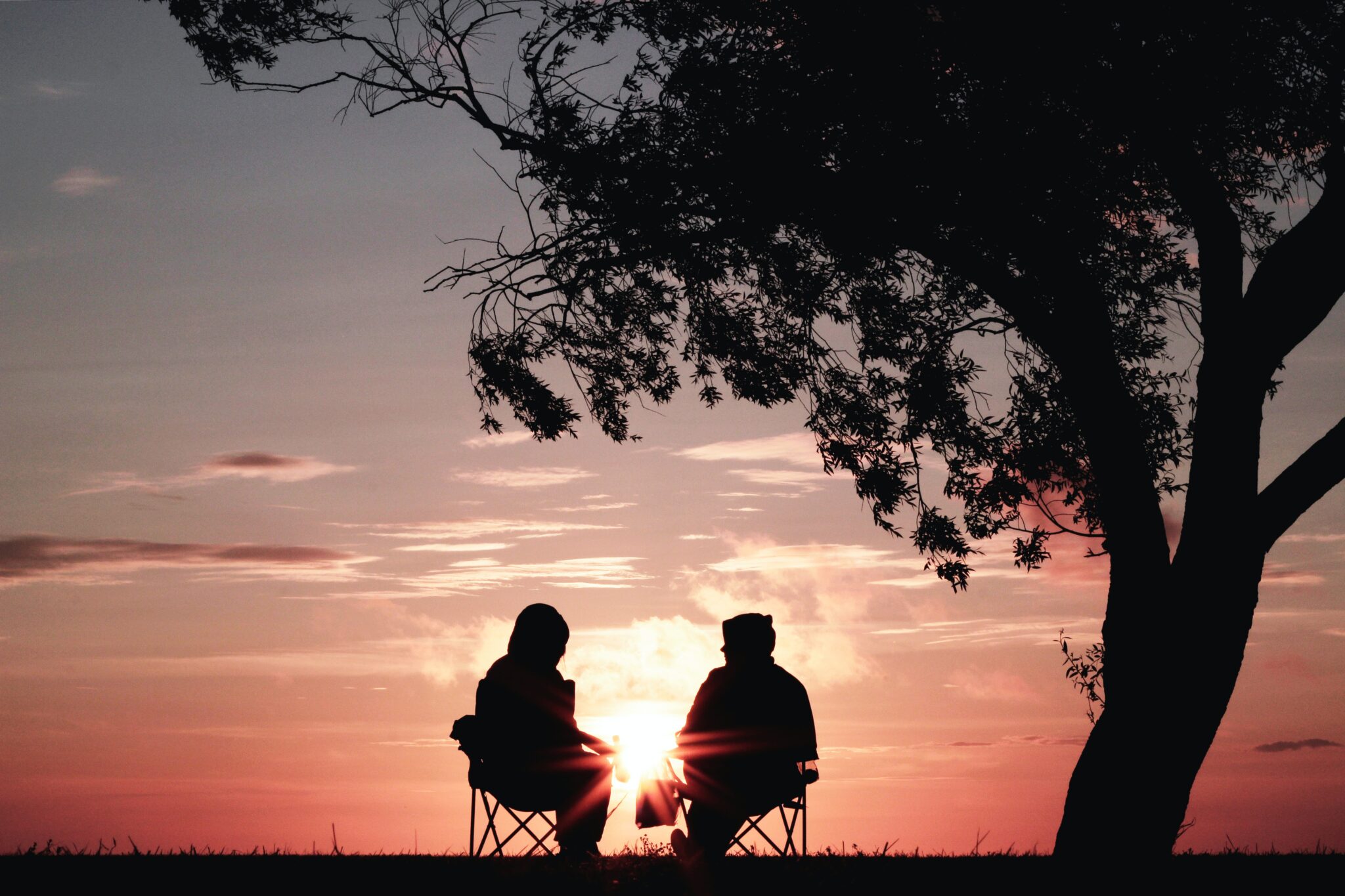 Two people sitting outside, watching the sunset