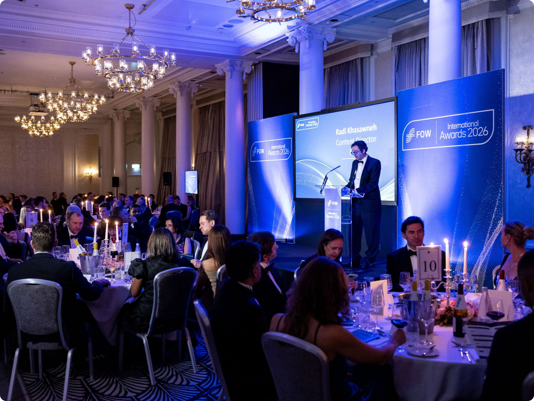 Formal awards ceremony in elegant ballroom with speaker at podium and seated guests.