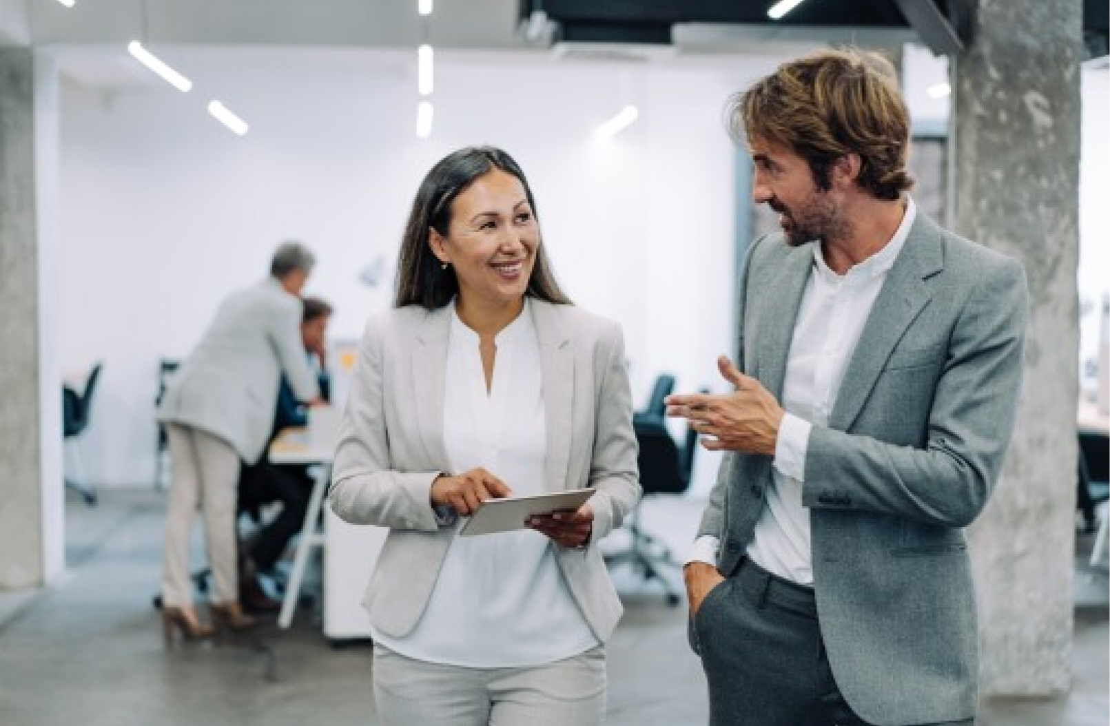 A woman using a tablet while talking to a man