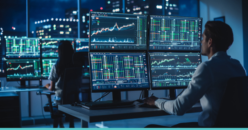 Man looking at monitors with trading graphs