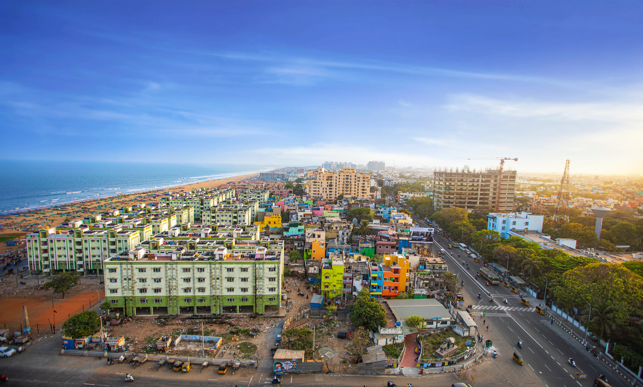 Aerial view of colourful coastal city with beach, buildings, and roads.