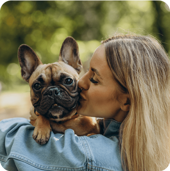 A woman lovingly kissing her bulldog, highlighting the importance of being aware of breed-specific health conditions and ensuring that pet insurance provides coverage for potential hereditary issues. Even mixed breed pets can be prone to genetic conditions.