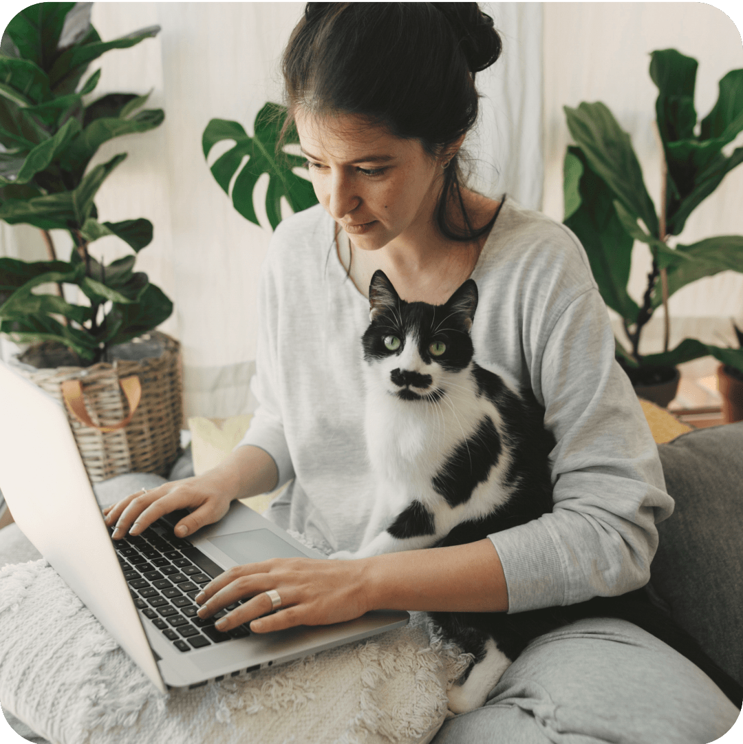 A woman pet owner is looking at the Annual Deductible while her tuxedo cat is sitting on her lap.