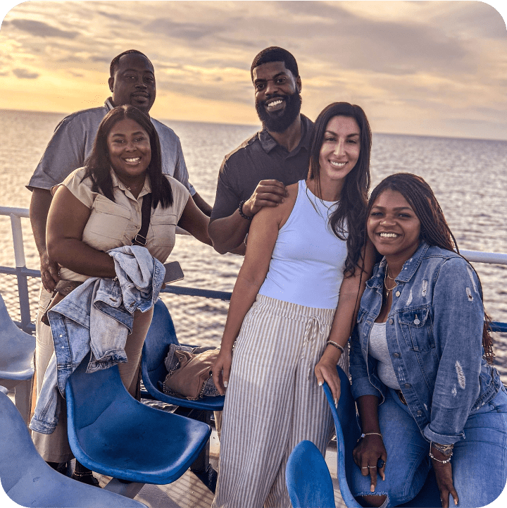 Embrace Pet Insurance employees enjoy a sunny day on a boat, showcasing diverse team members in casual attire smiling together, illustrating the company's emphasis on work-life balance and team bonding.