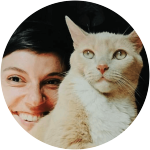 A human is posing with her white and orange cat looking so serious. 