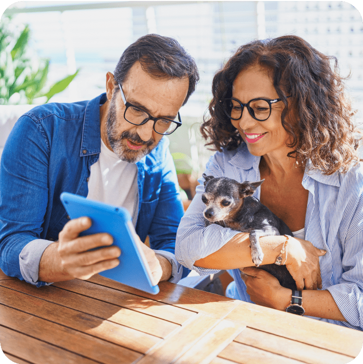 An elderly couple lovingly holding their mini-sized pet dog while exploring options for affordable pet insurance to ensure their furry friend's well-being.