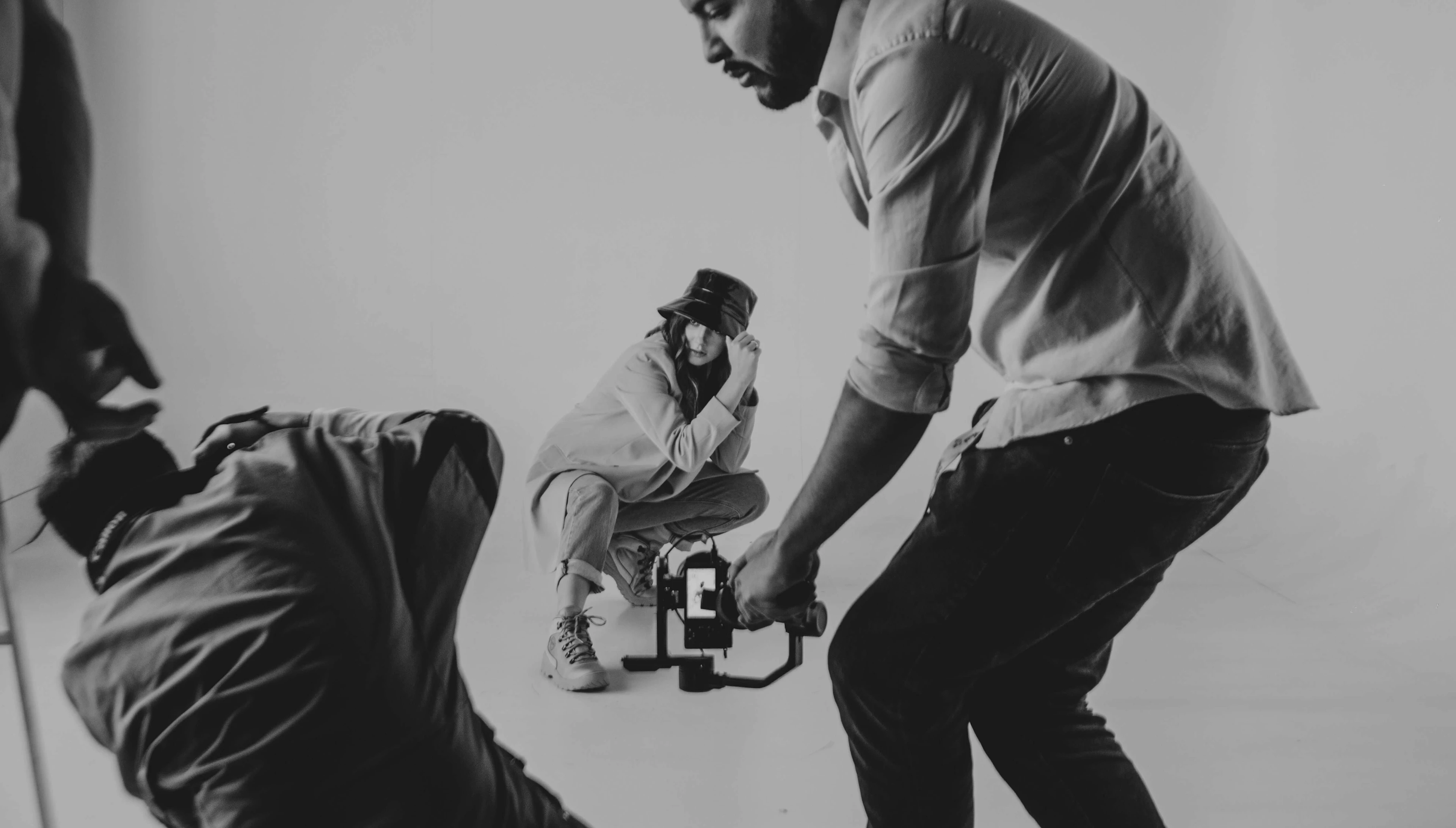 Black and white photo of photographers in action during a studio shoot with a crouching model.