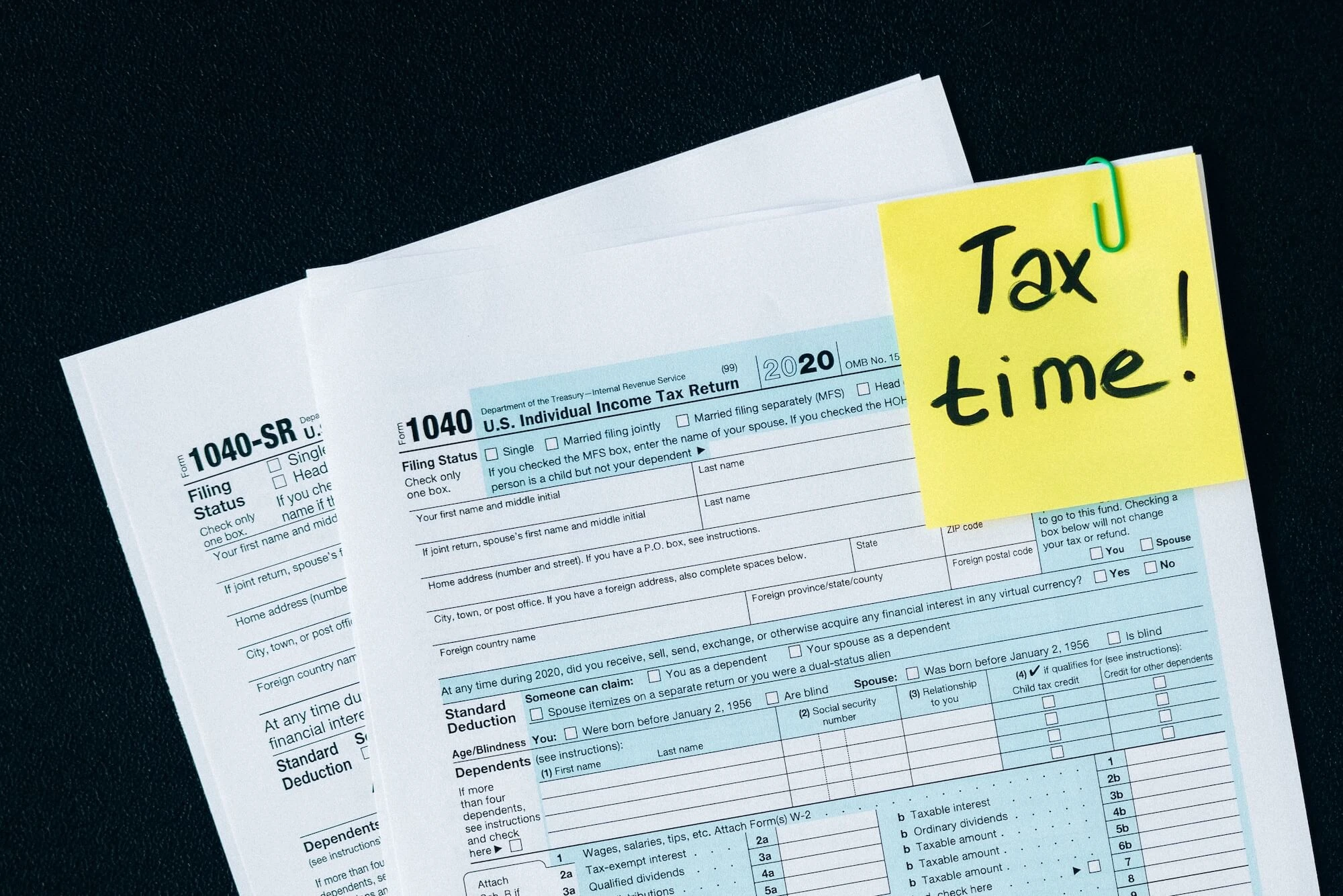 U.S. tax documents with a 'Tax time!' reminder, highlighting the importance of filing deadlines. Photo by Nataliya Vaitkevich.
