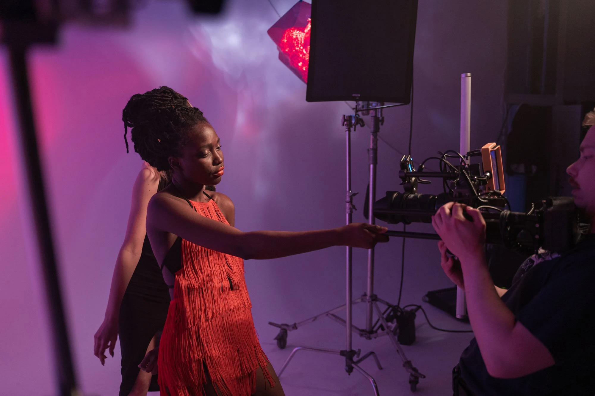 Photographer and crew on a paid studio shoot with a model in a red dress under dramatic lighting. Photo by ANTONI SHKRABA production