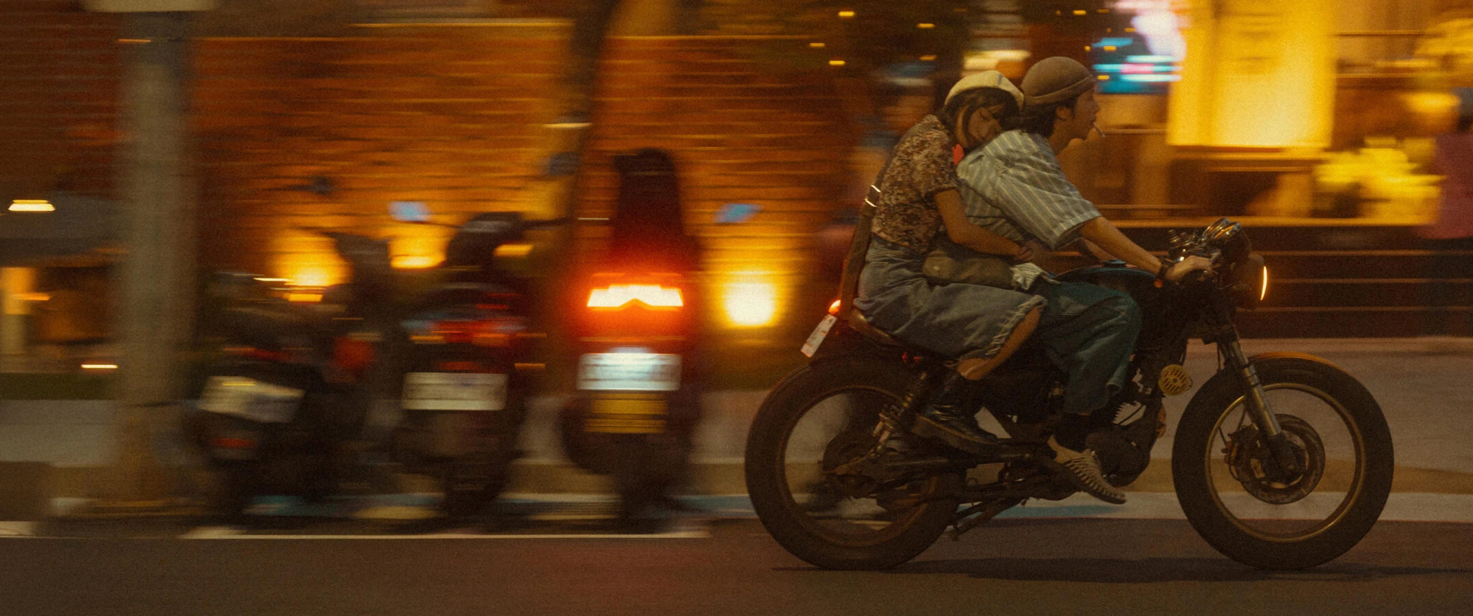 Couple riding a motorcycle through a city at night, showcasing creative lifestyle and travel photography enhanced by Narrative’s AI photo culling and editing software for professional photographers.