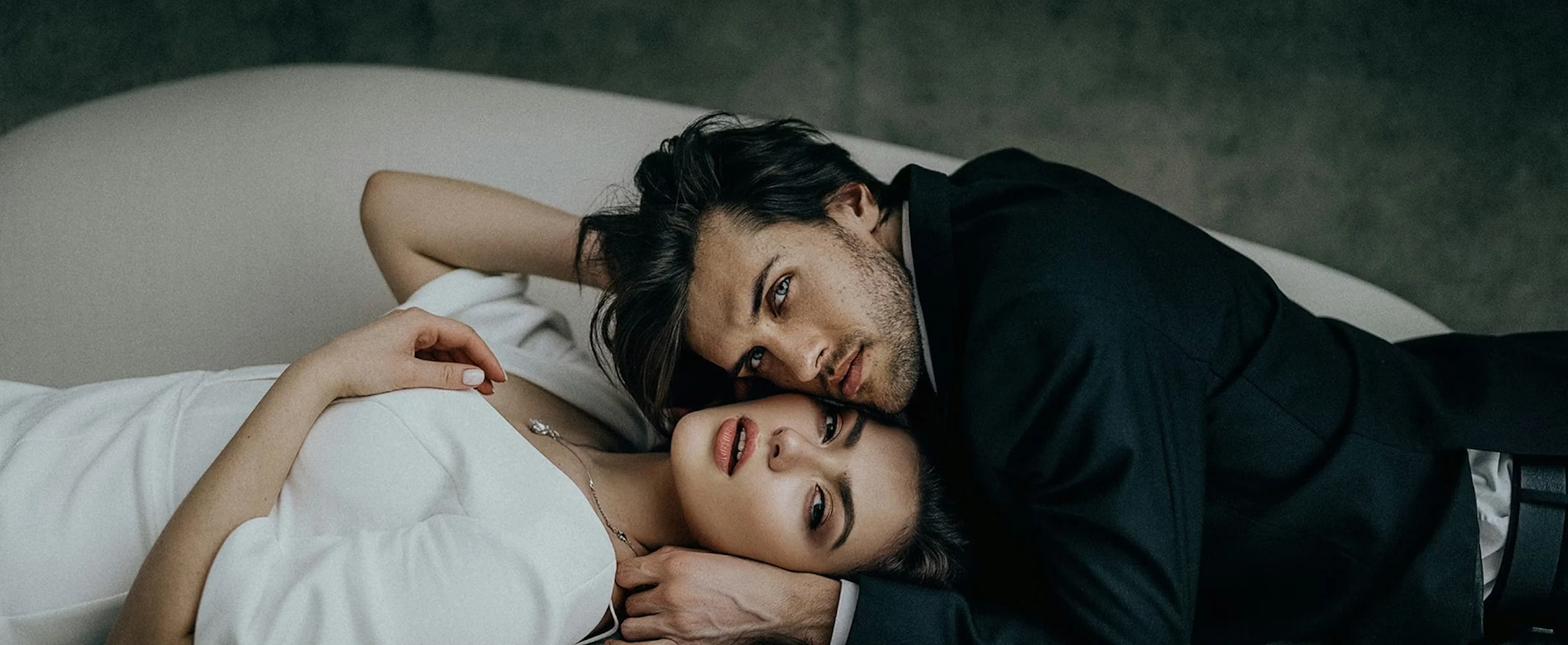 Intimate portrait of a couple lying together on white bedding