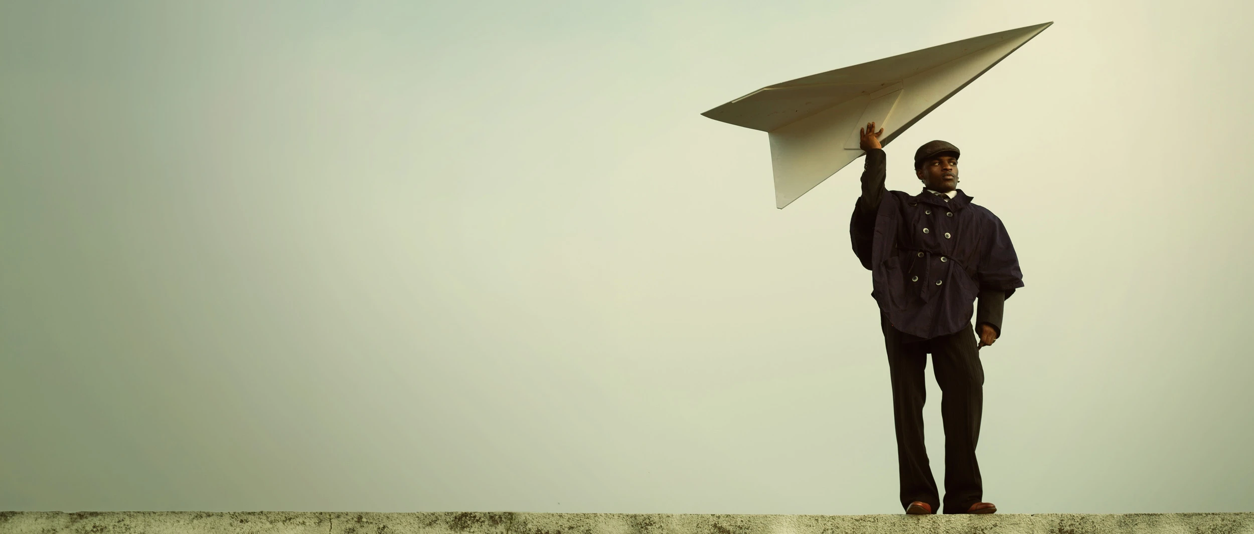 Editorial portrait by photographer Etim E Essang featuring a model holding a large paper airplane, showcasing creative photography enhanced by Narrative’s AI photo culling and editing software for professional photographers.