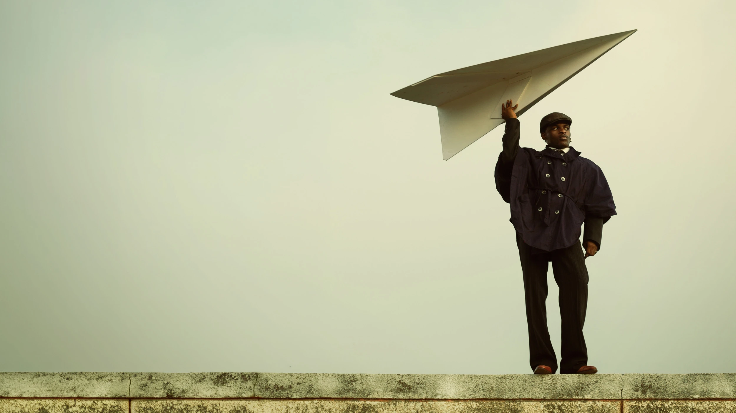 Editorial portrait by photographer Etim E Essang featuring a model holding a large paper airplane, showcasing creative photography enhanced by Narrative’s AI photo culling and editing software for professional photographers.